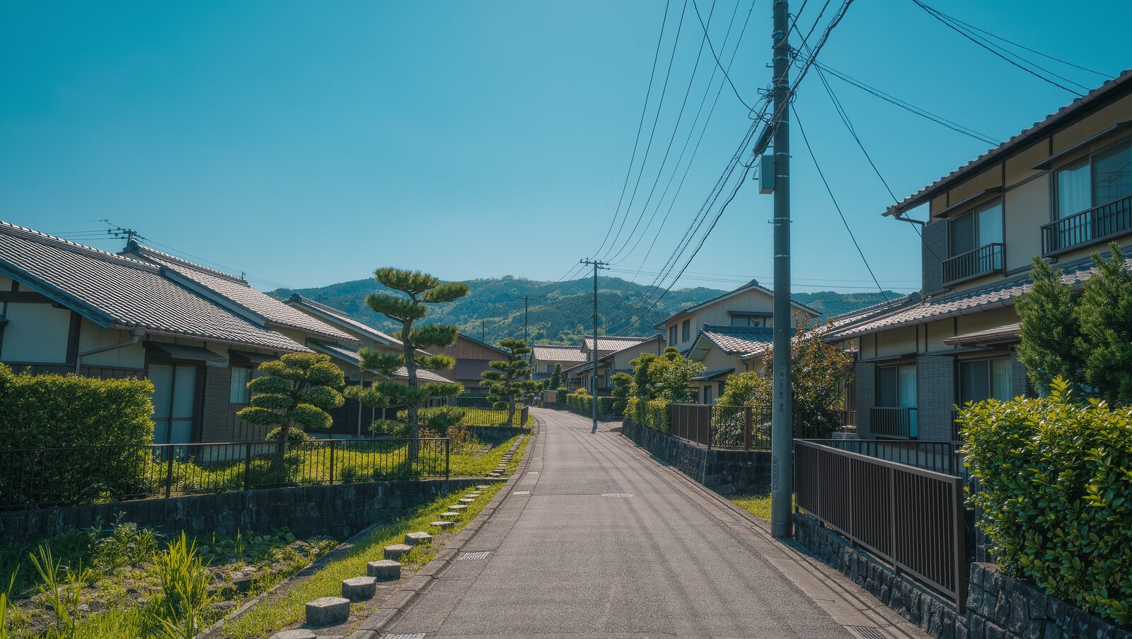 緑の山へ続く晴れた日の静かな住宅街の道