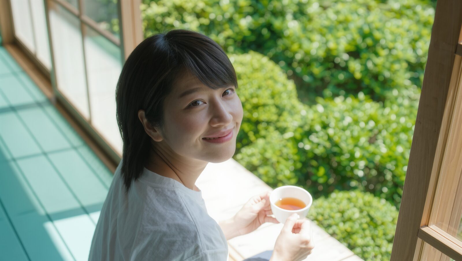 縁側でお茶を手に、満足そうにほほえむ女性
